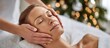 © Nina - Young woman enjoys a calming facial treatment at a spa, with hands of a massage therapist applying soothing techniques. Skincare routine. Christmas and New Year greetings. Beauty Salon. Wellness, spa