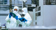 © metamorworks - Male and female workers in protective clothing inspecting silicon wafers while looking at a tablet in a semiconductor factory