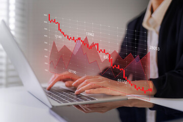 Wall Mural - Business professional analyzes stock market decline data on laptop computer during economic downturn period