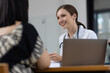 © Wasan - Female doctor is smiling at her pregnant patient during a consultation in a medical office, providing compassionate care and support