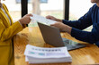 © Wasan - Businessman giving document to businesswoman in office meeting.