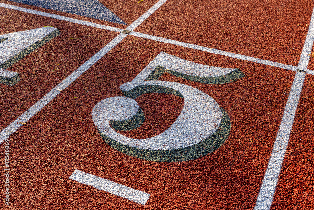 Close up photo of outdoor running track lane white number five, 5, with ...