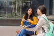 © Guillermo Spelucin - College students discussing study material outdoors