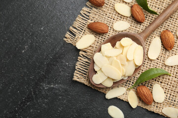 Wall Mural - Fresh almond flakes, whole nuts and green leaves on grey table, flat lay. Space for text