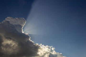 Wall Mural - Clouds in the blue sky with sun rays and lens flare.