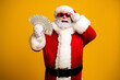 © deagreez - Santa Claus wearing sunglasses holding cash and smiling on a bright yellow background festive holiday portrait
