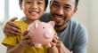 © Sandor - father and son smiling while holding a pink piggy bank in a bright living room