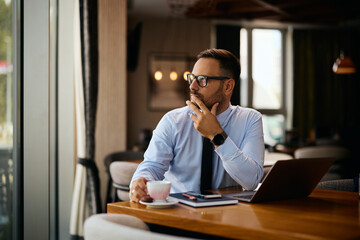 Thoughtful businessman having cup of coffee in cafe.