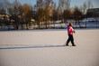 © StockMediaSeller - Elderly woman walking with trekking poles on a snowy frozen field in bright winter sunlight. She stays active and healthy, enjoying exercise and fresh air during a peaceful day outdoors.