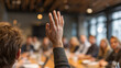 © Nattapol - Engaged businessman raising hand to ask question during business meeting. Active audience participation in corporate conference or seminar