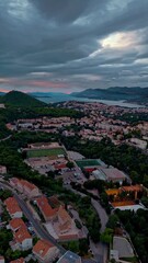 Wall Mural - Aerial mid-angle drone flies over Dubrovnik, capturing mountains, rolling hills, and autumn trees glowing warmly in golden sunset light across the scenic Croatian landscape.