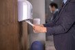 © Apichat - Businessman drying hands with paper towels in office restroom