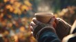 © imagemir - A woman holds a warm cup in a cozy sweater, surrounded by golden autumn leaves, creating a serene and inviting atmosphere.