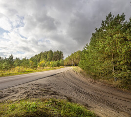 Wall Mural - Road with a dirt road and trees in the background