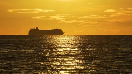 Wall Mural - Ferry Sails Orange Sunset Over the Horizon, Waves Reflecting a Meditative Mood