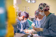 © BusinessClass by W61 - Team of surgeons wearing masks performing surgery on patient in emergency room