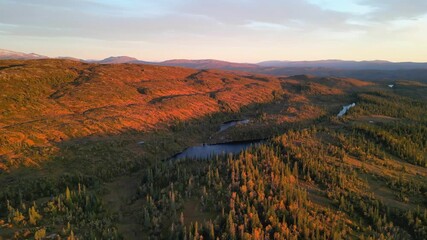Wall Mural - Aerial view of sunset over forested hills and small mountain lakes.