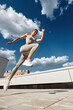 © Georgii - Athletic woman leaps in midair on a rooftop under a bright blue sky