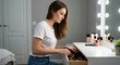 © Iryna - Woman organizing makeup drawer in bright bedroom with vanity table, personal care routine and home organization