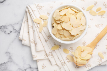 Wall Mural - Fresh almond flakes on white marble table, top view. Space for text