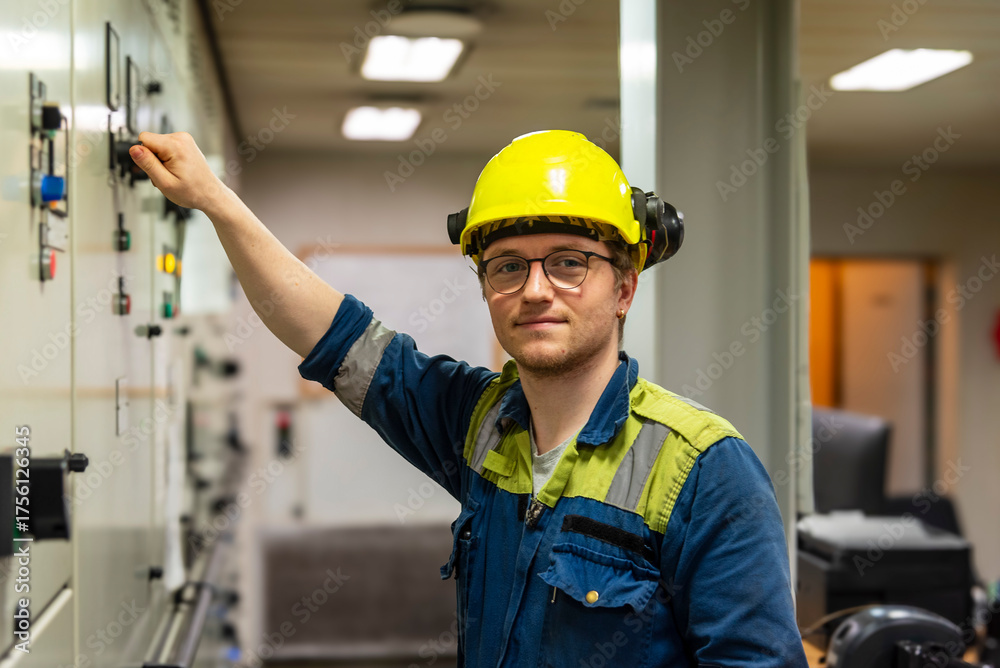 Young marine engineer in front of control panel during his daily ...