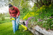 © Johnér - Woman cutting grass with weed trimmer in back yard