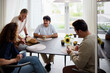 © Johnér - Smiling senior woman serving bread to family sitting around dining table at home