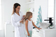 © New Africa - Mother brushing her daughter's hair in bathroom