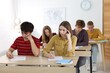 © New Africa - Students taking exam at wooden table indoors