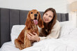 © New Africa - Pet friendly hotel. Woman and her cute dog in bed indoors