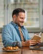 © Miljan Živković - Man reading book enjoying snack and relaxing in kitchen