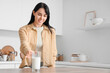 © Pixel-Shot - Beautiful young woman taking glass of milk from table in kitchen