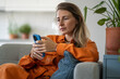 © DimaBerlin - Middle-aged woman deeply focused on phone browsing content with calm, deliberate expression. Female experiencing quiet concentration and relaxation finding enjoyment in information or online shopping
