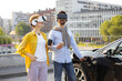 © sofiko14 - A couple wearing VR headsets while an electric vehicle charges in an urban setting.