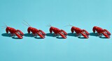 Five vibrant red crustaceans are arranged in a row against a turquoise background, shadows cast