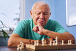 © Westend61 - Older man concentrating on chess game at table indoors