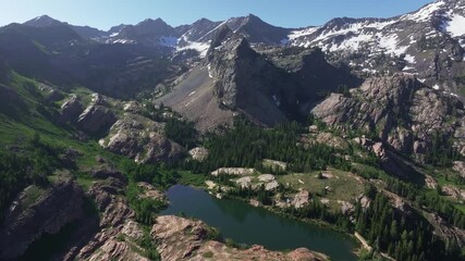 Wall Mural - Aerial drone trucking left wide shot of Lake Blanche in Big Cottonwood Canyon near Salt Lake City, Utah, on a bright green summer morning with rocky peaks, lush foliage and Sundial Peak towering above