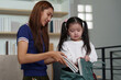 © itchaznong - Back to School. Mother helping daughter pack school supplies into backpack.