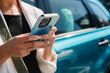 © Westend61 - Businesswoman using smartphone outdoors near blue car
