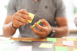 © Studio Marmellata - A person is holding and arranging colorful sticky notes on a desk, symbolizing planning and organization.