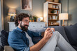 © Migma_Agency - Smiling man relaxing on couch writing notes