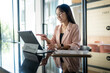 © Apichat - Businesswoman working with tablet and financial reports in modern office