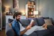 © Migma_Agency - Happy man relaxing on living room couch reading book