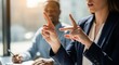 © hobonski - A businesswoman uses a clear hand gesture to emphasize a point during a discussion or meeting with a colleague in a sunlit professional office.