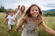 © Crowded Studio - Familia en movimiento al aire libre, capturando energía compartida, vínculo afectivo y libertad en entorno natural.Sonrientes corren tomadas de la mano en campo verde, fondo de árboles y colinas.