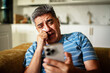 © Marko Geber - Middle-aged man crying while looking at phone