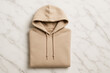 © Chanita - Minimalist folded beige hoodie on marble background fashion flat lay apparel design cozy streetwear clothing photography with soft texture and casual style