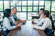 © Ekkasit A Siam - Senior asian restaurant owners discussing work strategy with young employees across table teamwork communication collaboration small business planning management partnership leadership meeting