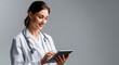 © EdwinGrandas - Smiling female doctor using digital tablet against gray background with copy space. Concept of modern healthcare, technology and medical innovation