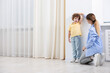 © New Africa - Mother measuring her little son’s height near white wall at home. Space for text